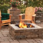Beautiful fire pit with adirondack chairs and green blanket.